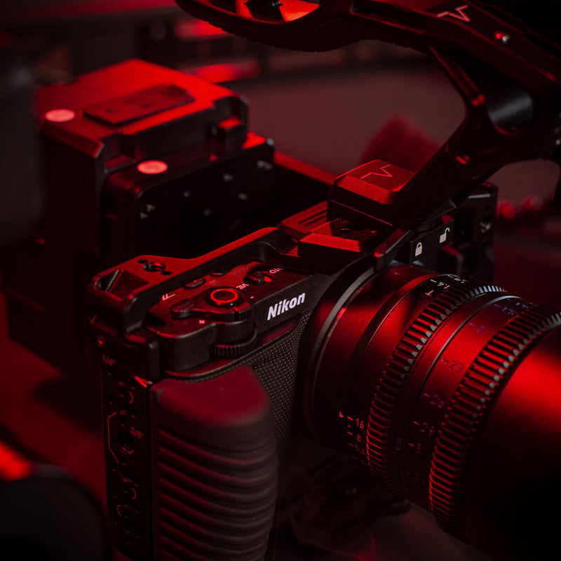 SHAPE Nikon ZR camera cage close-up showing 1/4-20 and 3/8-16 threaded mounting points in red cinematic lighting with a close up on handle