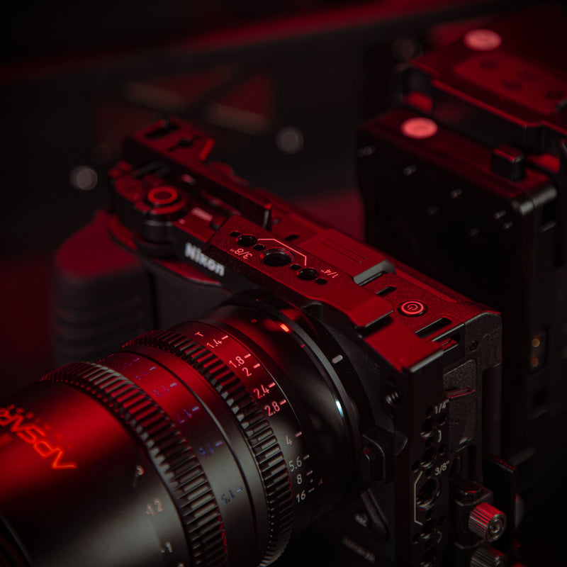 SHAPE Nikon ZR camera cage close-up showing 1/4-20 and 3/8-16 threaded mounting points in red cinematic lighting with a specs view