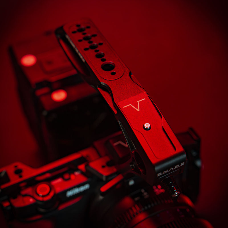 SHAPE Nikon ZR camera cage close-up showing 1/4-20 and 3/8-16 threaded mounting points in red cinematic lighting with the top handle